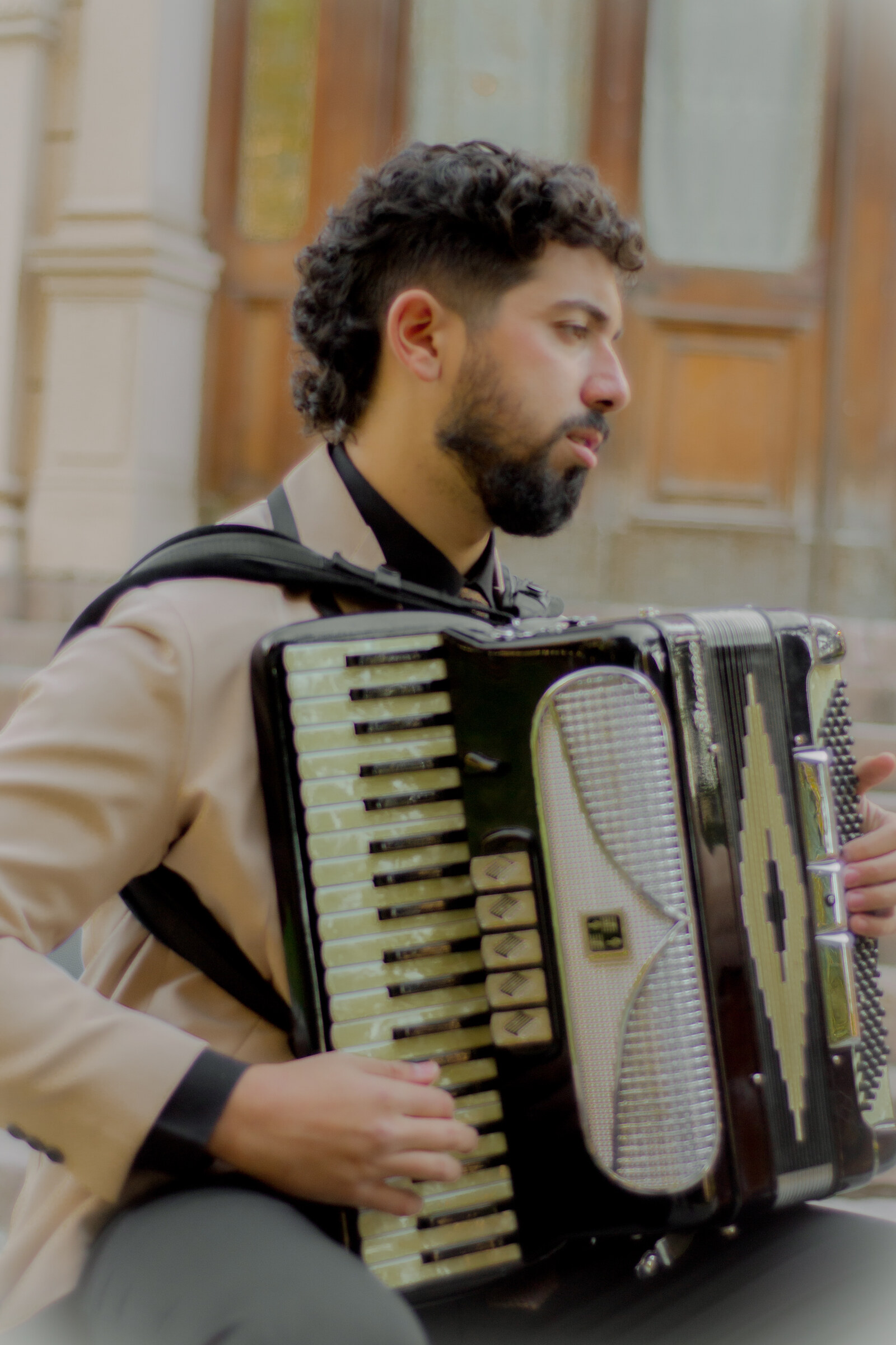 Músico del Dúo Amores de Chile tocando el acordeón con expresión serena en el Palacio Cousiño.