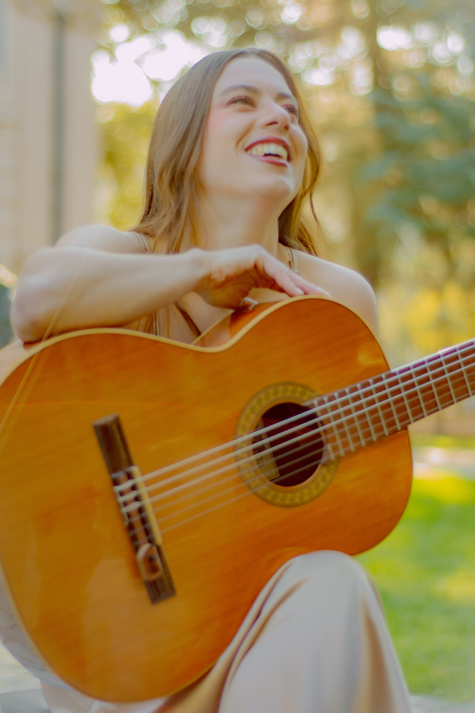 La vocalista del Dúo Amores de Chile sonríe alegremente mientras toca su guitarra acústica al aire libre.